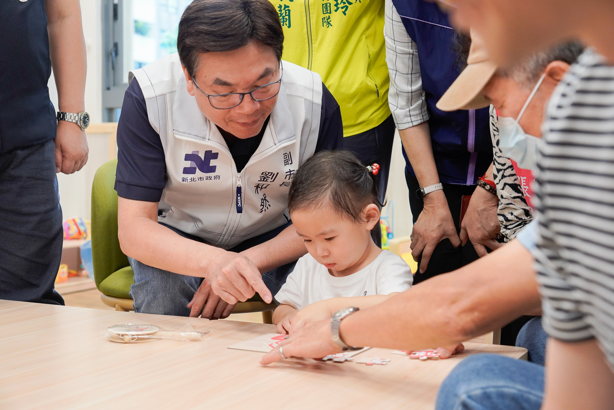  劉和然副市長在第127家中和安邦公托啟用上 要與小朋友一起玩拼圖